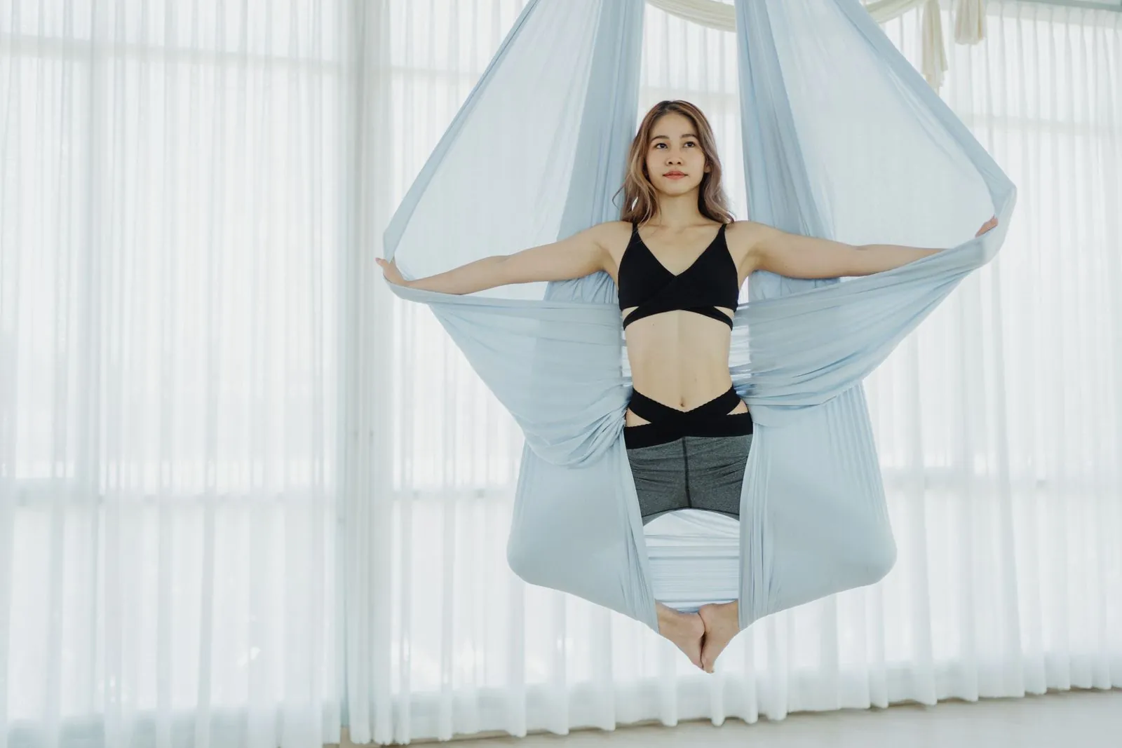 Aydınlık bir stüdyoda hamak yoga yapan kadın